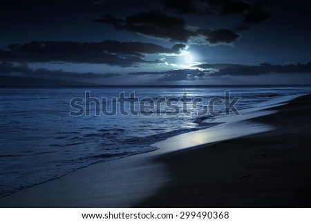 This photo illustration depicts a quiet and romantic moonlit beach in Maui Hawaii. It could represent any beach at night with calm waves and cloud filled night time sky.
