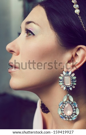 Fashion portrait of beautiful young woman with  tiara and earrings framed with precious stones