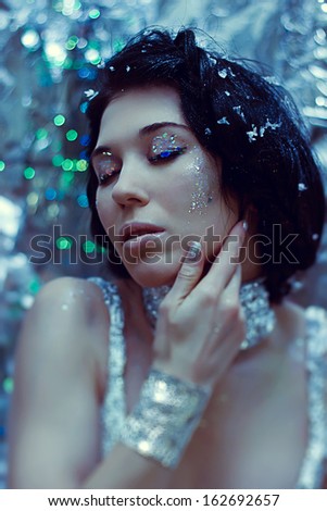 Portrait of winter beautiful young woman with silver makeup in silver clothes