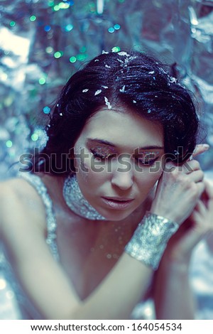 Portrait of winter beautiful young woman with christmas makeup in silver clothes