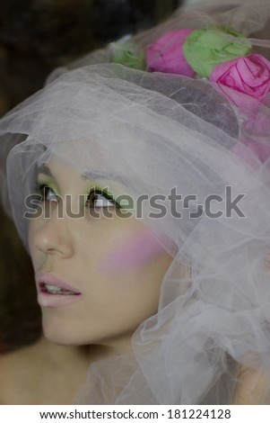 Portrait of beautiful young woman in white veil and  headdress of flowers. Makeup in green and pink colors. Tenderness. Bride