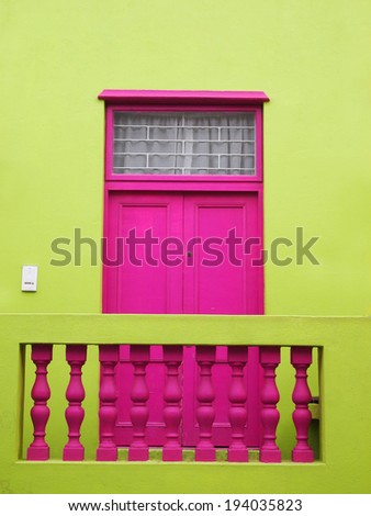 Part of the wall of the house. Door to balcony. Bright colors. Deep pink and yellow-green. Bo-Kaap. Malay Quarter. Cape Town. South Africa