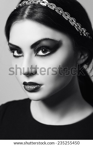Close up  white black portrait of young beautiful  brown-eyed woman with long black hair on white background. Arab woman. Scarlet makeup and black arrows. Fashion model shooting. Silver jewelry.