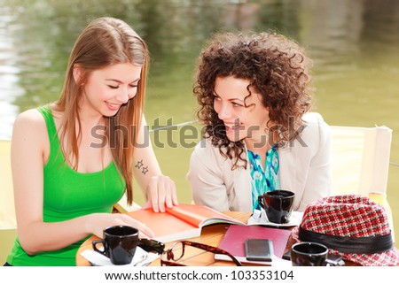 Two beautiful women chatting over a coffee at the river side terrace