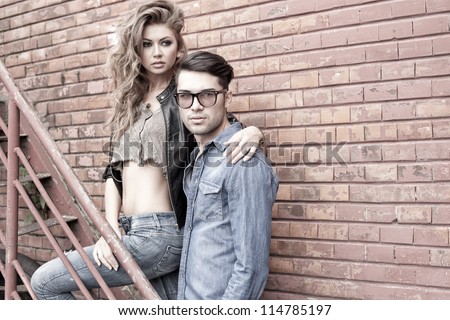 Sexy and fashionable couple wearing jeans, shoot in a grungy location - landscape orientation with copy-space - stock photo