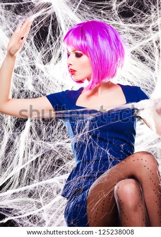 sexy model with purple wig and intense make-up trapped in a spider web - fashion shoot