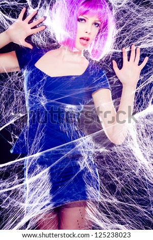sexy model with purple wig and intense make-up trapped in a spider web - fashion shoot
