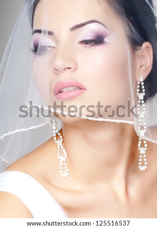 beautiful bride portrait with veil over her face, wearing professional make-up