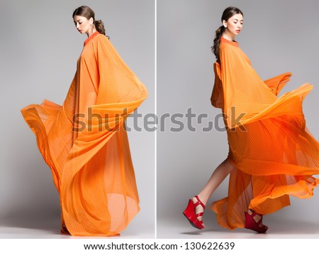 beautiful woman in long orange dress posing dynamic in the studio