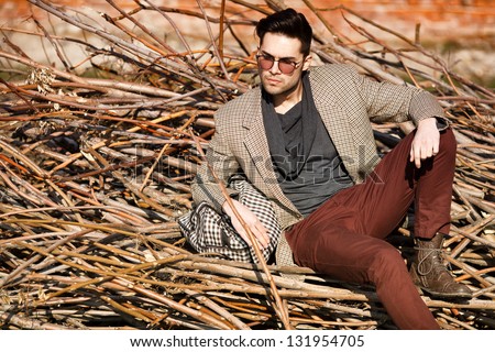 sexy fashion man model dressed elegant holding a bag posing outdoor