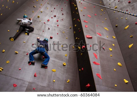two young people climbing on wall