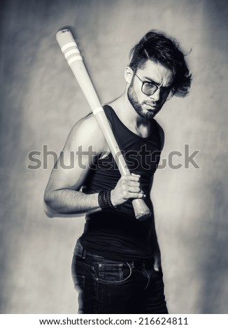 sexy fashion man model with a baseball bat looking angry against grunge wall