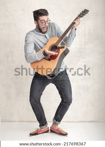 handsome funny man playing an acoustic guitar against grunge wall