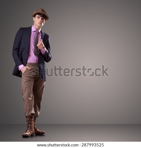 Attractive young male model dressed in vintage clothes isolated on gray background