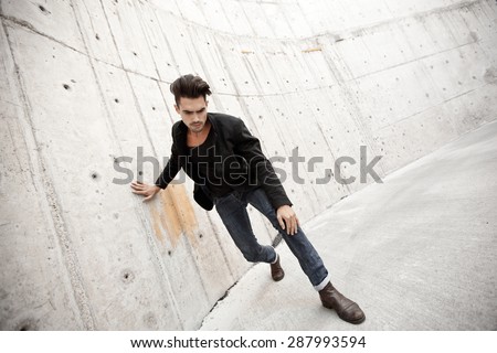 Attractive man dressed in jeans and boots in a grungy scenery