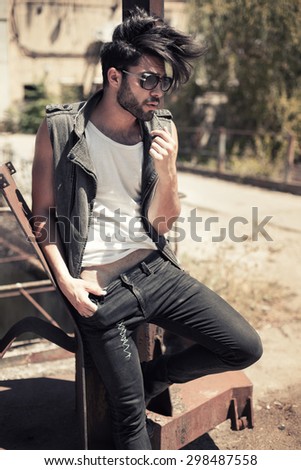 handsome man model dressed punk, hipster posing dramatic in grunge location