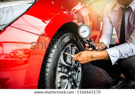 Asian man car inspection Measure quantity Inflated Rubber tires\
car.Close up hand holding machine Inflated pressure gauge for car tyre\
pressure measurement for automotive, automobile image