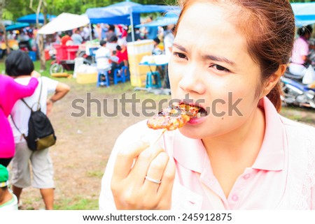 pretty girl eating grilled pork and sticky rice in thailand