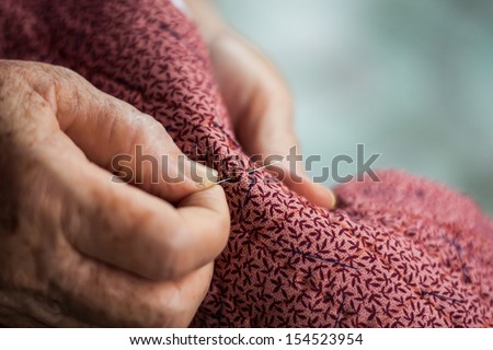 Hands of elderly sewing bags as a hobby