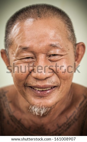 An asian old man happy face smiling and his body full of tattoo
