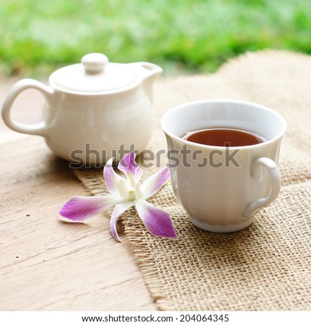 cup of black coffee  with purple orchid and burlap cloth on wooden table