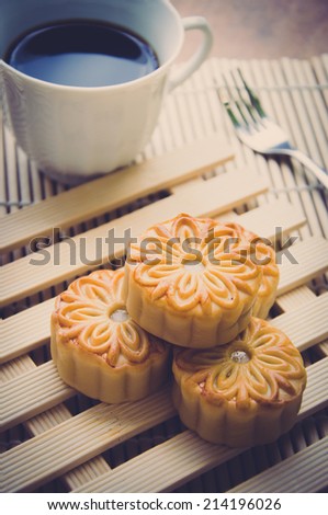 Retro vintage style Chinese mid autumn festival foods. The Chinese words on the mooncakes means assorted fruits nuts. Traditional mooncakes on table setting with coffee cup