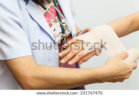 Rescuer bandaging upper limb of young woman