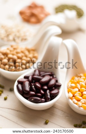 Different kinds of bean seeds, lentil, peas in dish on wooden table, macrobiotic food or healthy food
