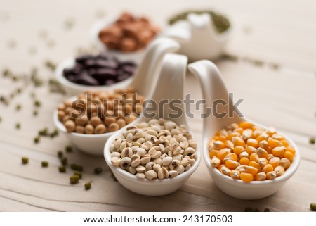 Different kinds of bean seeds, lentil, peas in dish on wooden table, macrobiotic food or healthy food