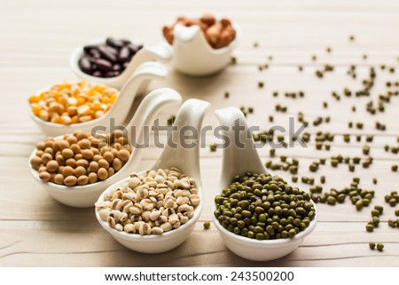 collection set of beans, legumes, peas, lentils on ceramic spoons on white wooden background