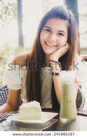 Woman at cafe thinking happy and smiling. Young beautiful Asian female model. Image is cross-processed giving retro style.