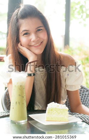 Woman at cafe thinking happy and smiling. Young beautiful Asian female model. Image is cross-processed giving retro style.