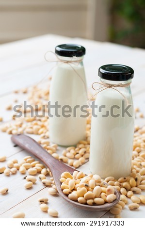 Soy milk [Soya milk ] in  glass bottle with soy pods on white wooden background, healthy drink