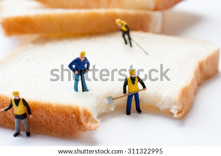 A tiny model figure of a foreman directs his miniature team with bread