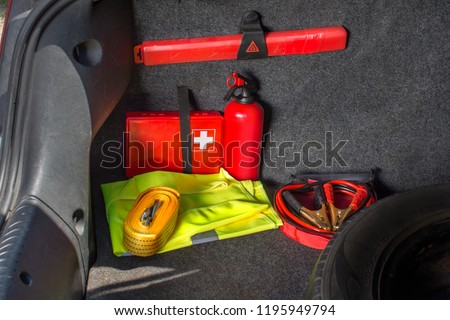 The interior of the trunk of the car in which there is a first aid kit, fire extinguisher, warning triangle, reflective vest, starter cables and tow rope.