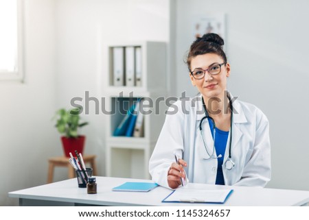 Doctor on her job in Medical Office looking at Camera
