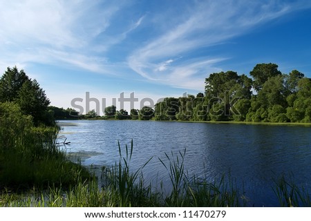 Summer river bank view with blue sky and light clouds