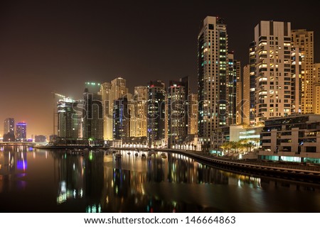 High rise apartments against the dark night. Calm water of the artificial canal reflects skyline