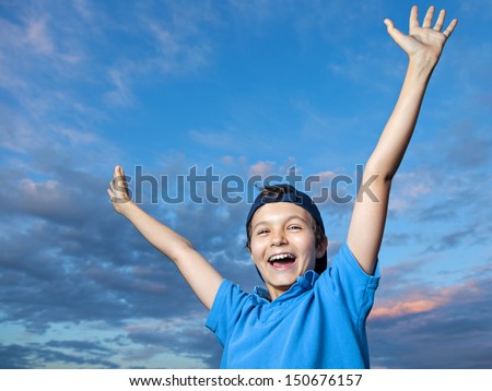 Teenage boy, standing outside, its evening, he is very happy, throwing his arms up in the air