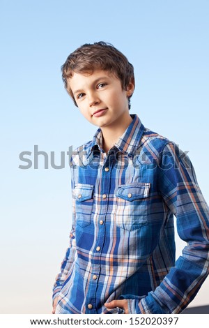 A teenage boy is making a cool pose and is smiling friendly into the camera.