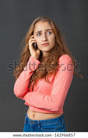 Teenage Girl with beautiful long curly hair. She talks on her mobile phone.