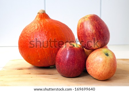 Pumpkin and four apples on a wooden board
