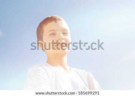 Portrait of a cool confident boy standing outside. Picture from low angle view in retro vintage look