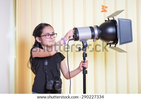 Little cute girl learning the lighting technique in a photostudio