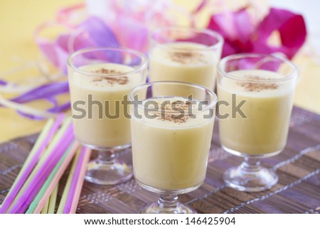 Fresh mixed mango juice glass with an ice and honey on a brown wooden mat