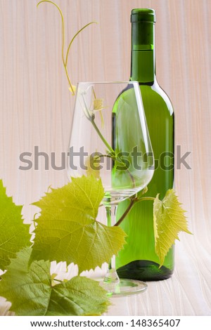 White wine bottle presented with wine glass on a orange background