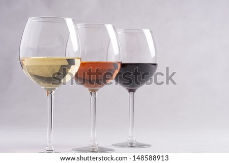Three wine glasses with different wines - red, rose and white on a solid background