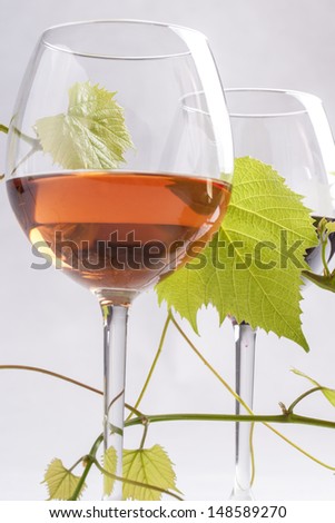 Three wine glasses with different wines - red, rose and white with grape leafs on a solid bright background