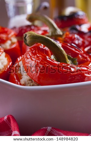Red peppers stuffed with rice and meat placed in deep white casserole