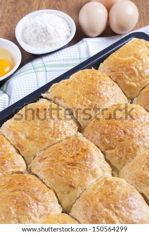 Fresh baked wheat rolls in black sheet tray on a white dish towel